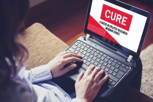 Woman sitting at a laptop participating in a CURE webinar.