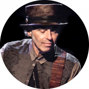 The legendary Nils Lofgren looks down toward his guitar while performing.